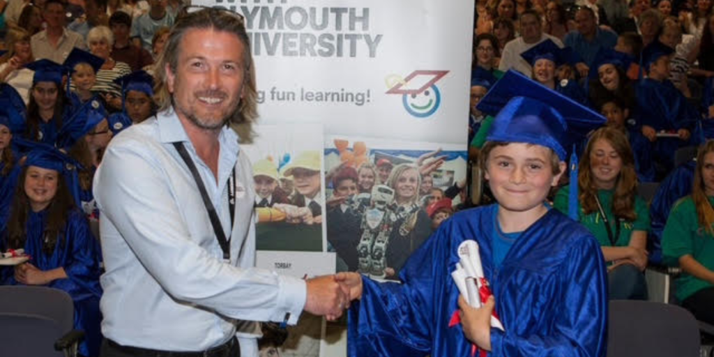 David Lawrence Jones presenting a graduation certificate to a young student at a children’s literacy event